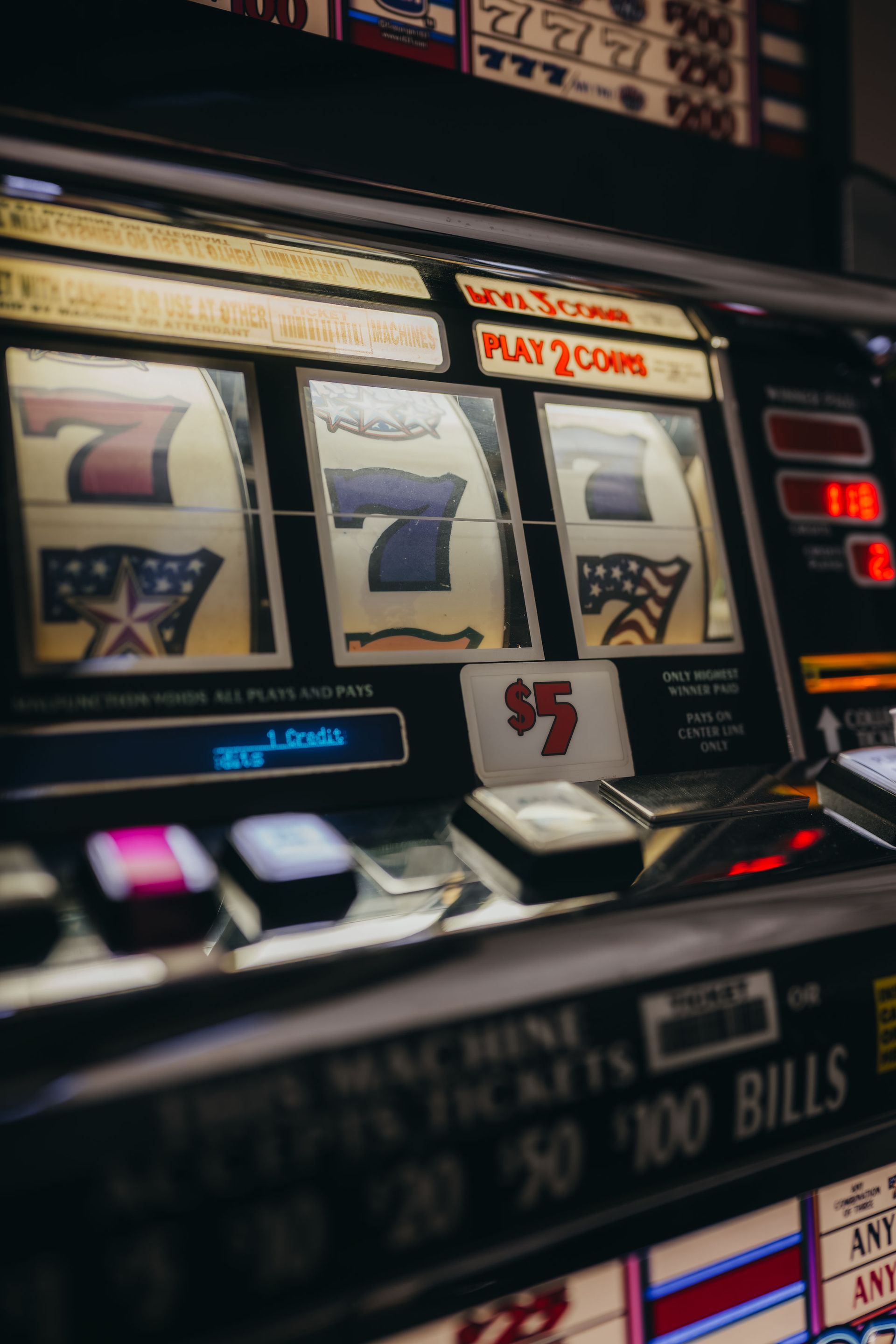 Slot machine with three reels showing sevens and stars; coin slot visible.