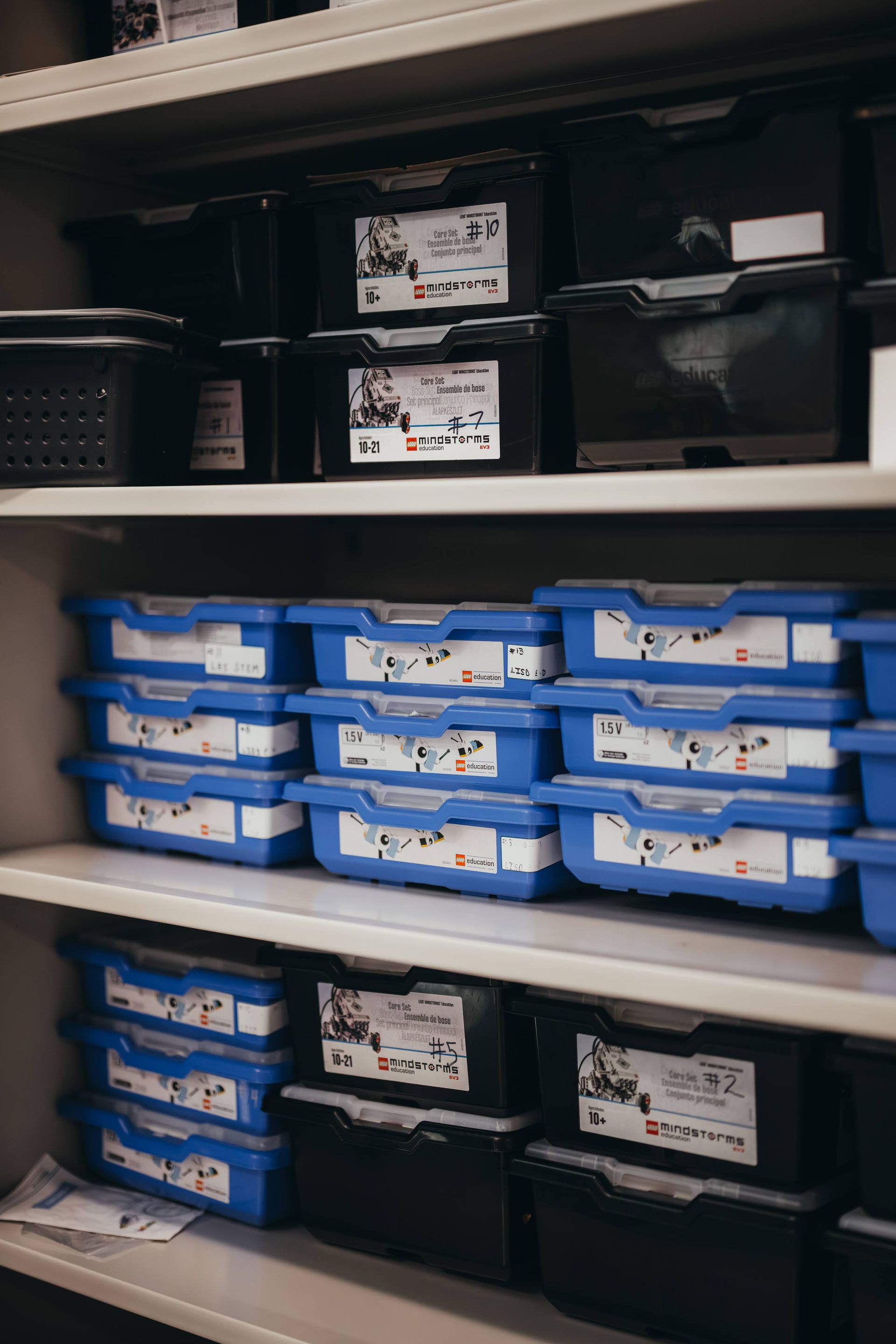 Shelves filled with blue and black LEGO storage bins.