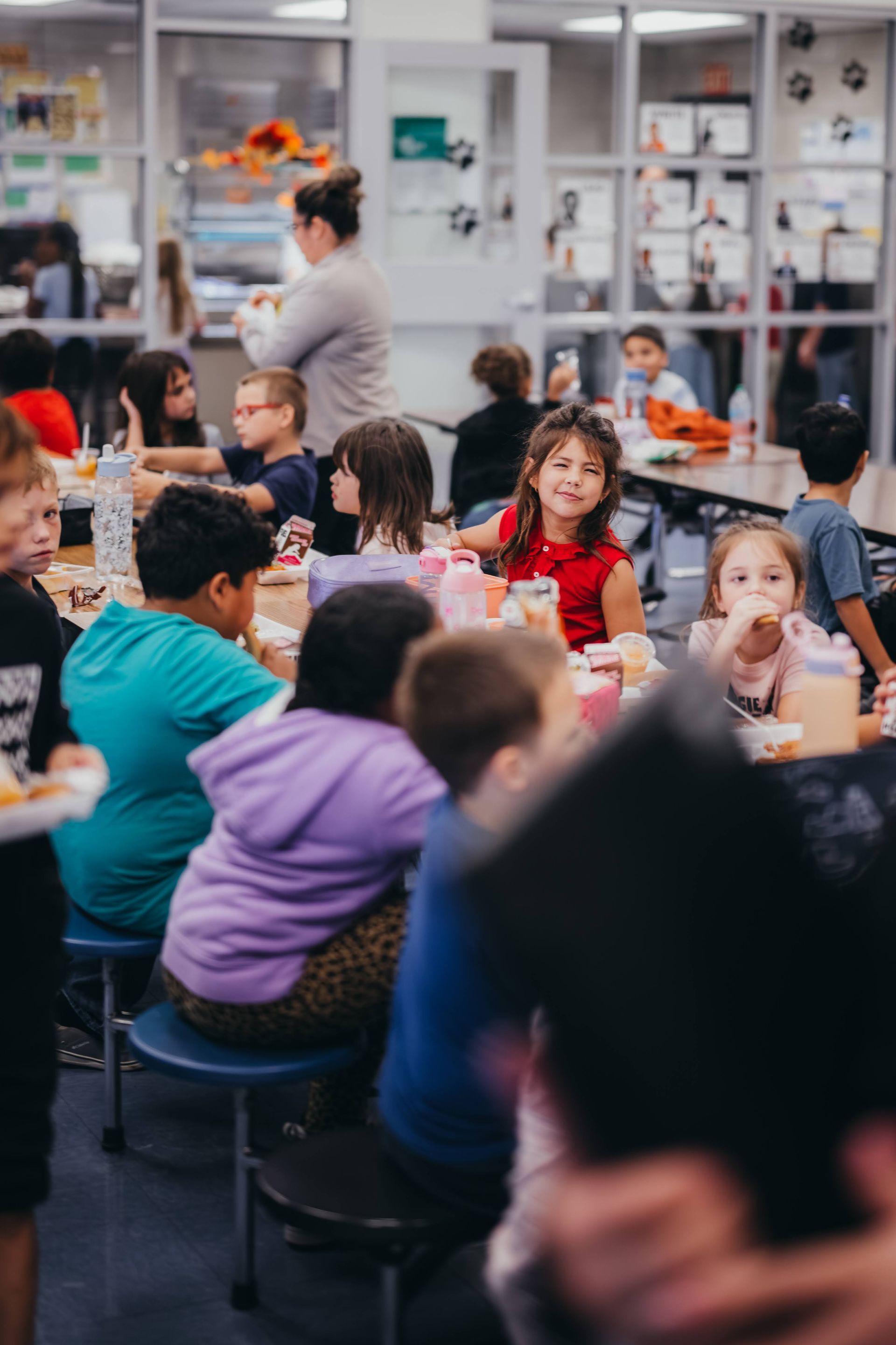 Children eating lunch at tables in a school cafeteria.