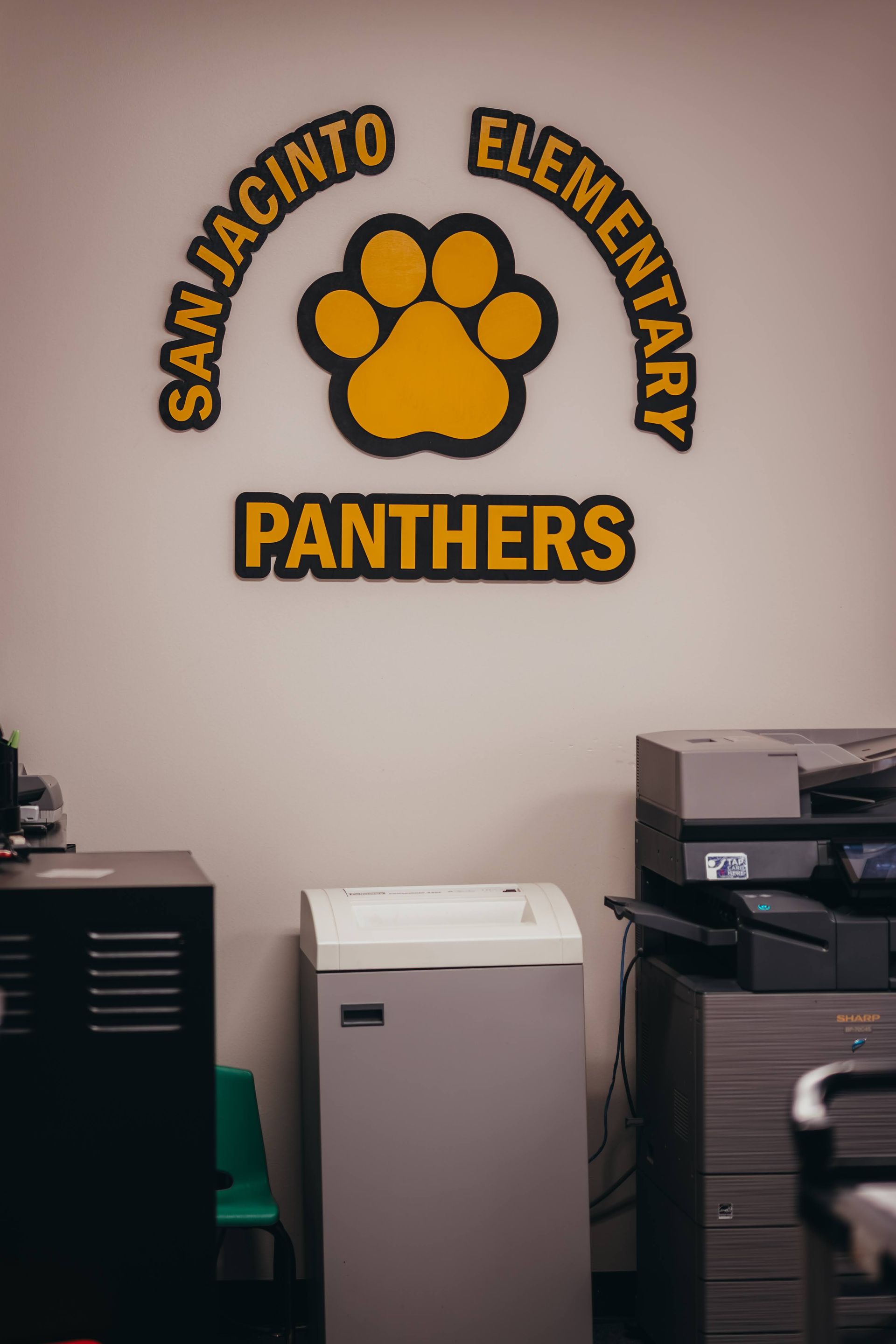San Jacinto Elementary Panthers logo above a paper shredder and printers in an office.