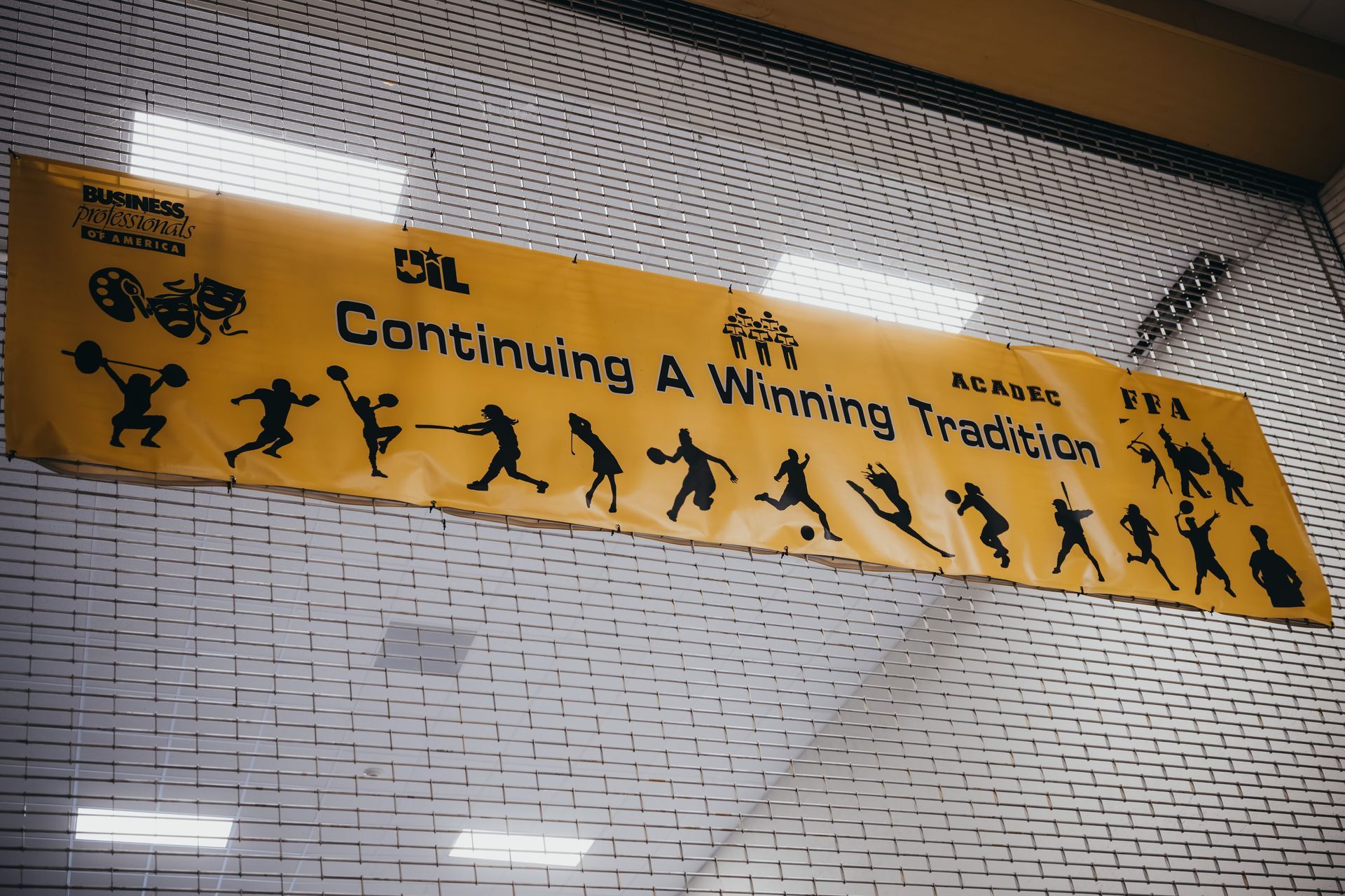 Yellow banner with black silhouettes of sports figures