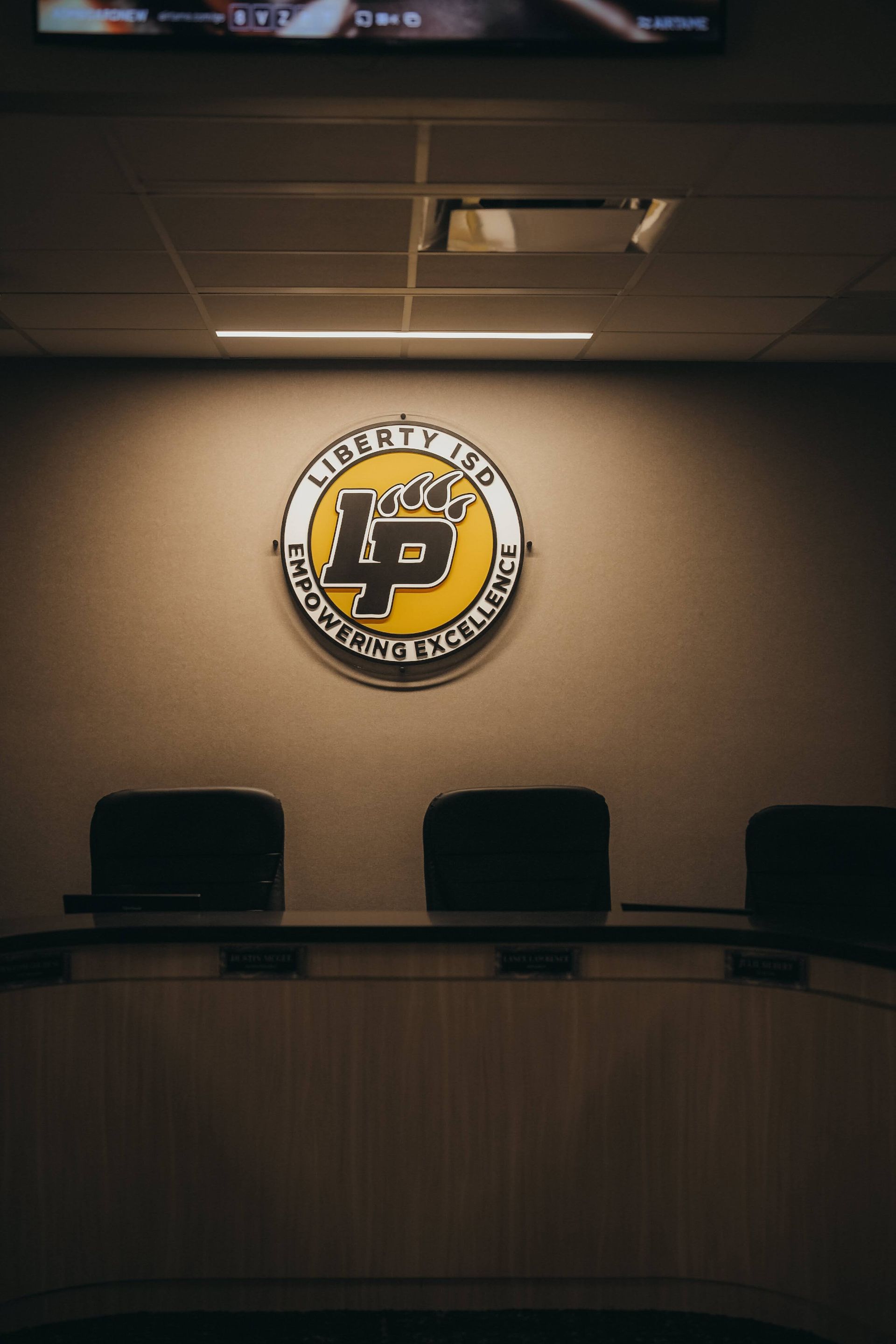 Round LP logo with text on brown wall above a conference table and chairs.