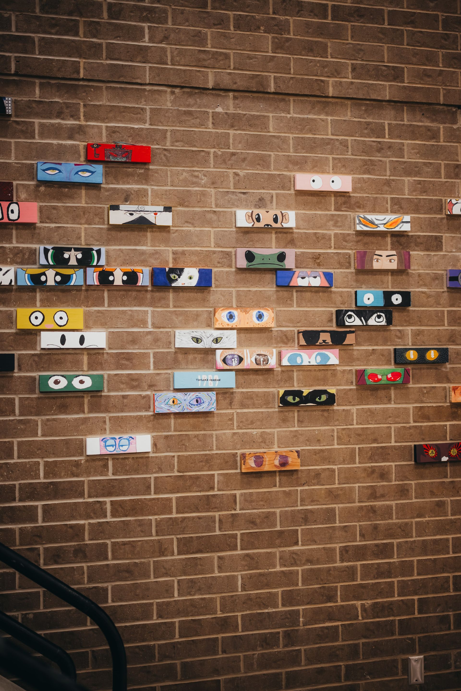 Brick wall decorated with colorful, rectangular artwork resembling cartoon eyeglasses.