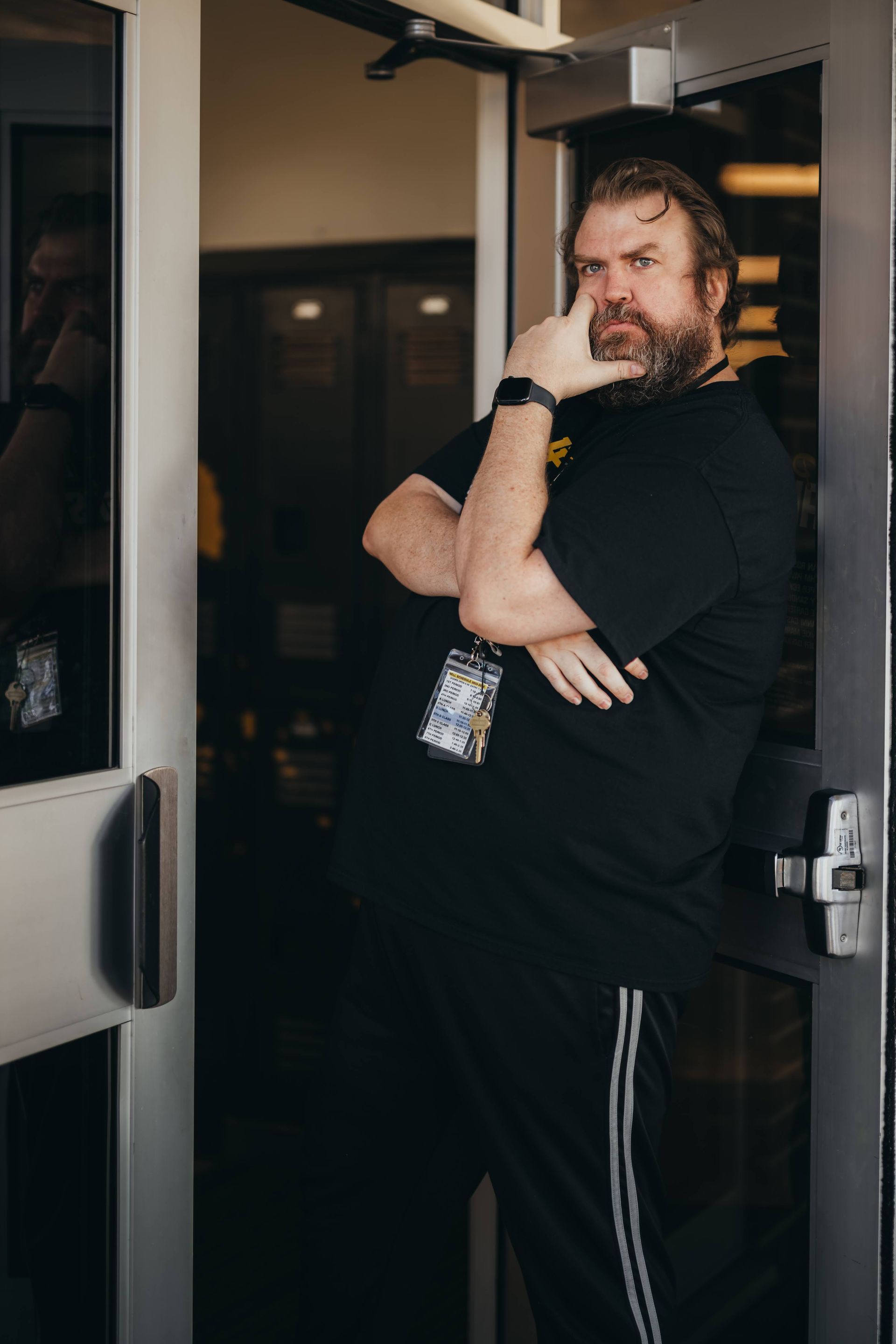 Man in black leaning on doorway, pondering.
