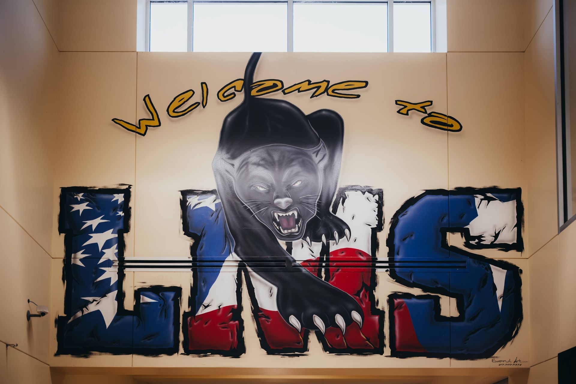 Welcome sign with a panther leaping over the letters L, H, S, painted with American flag colors.