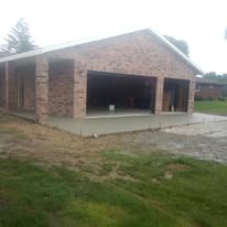 Brick house with a covered front porch and open garage on a grassy lot