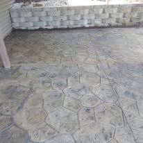 Empty patterned stone patio with a low brick wall in the background.