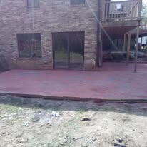 Brick house patio with two glass doors and an upper balcony staircase