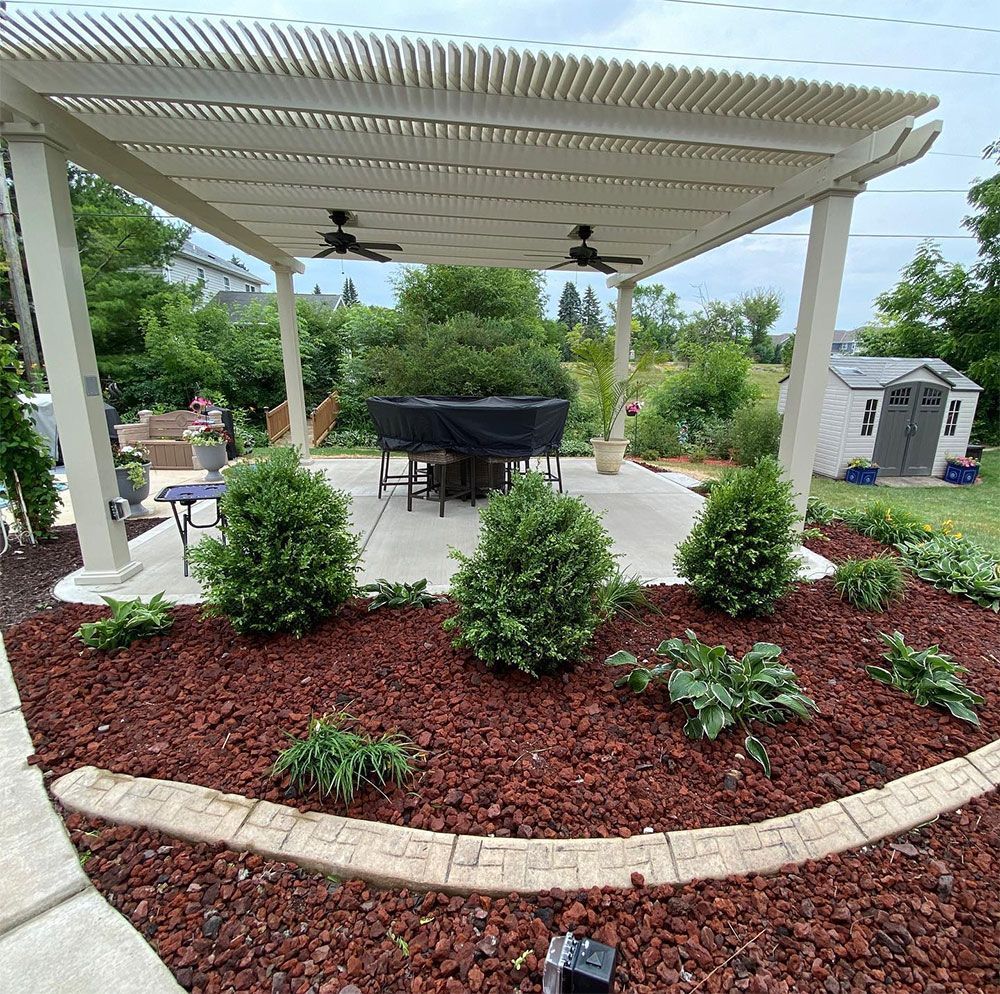 A patio with a white pergola, a dining set, and hanging flower baskets overlooking a backyard with a swimming pool.