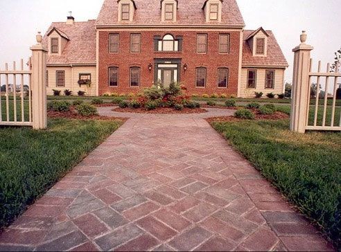A stone retaining wall with tiered garden beds, stone steps, and lush green landscaping leading to a house patio.