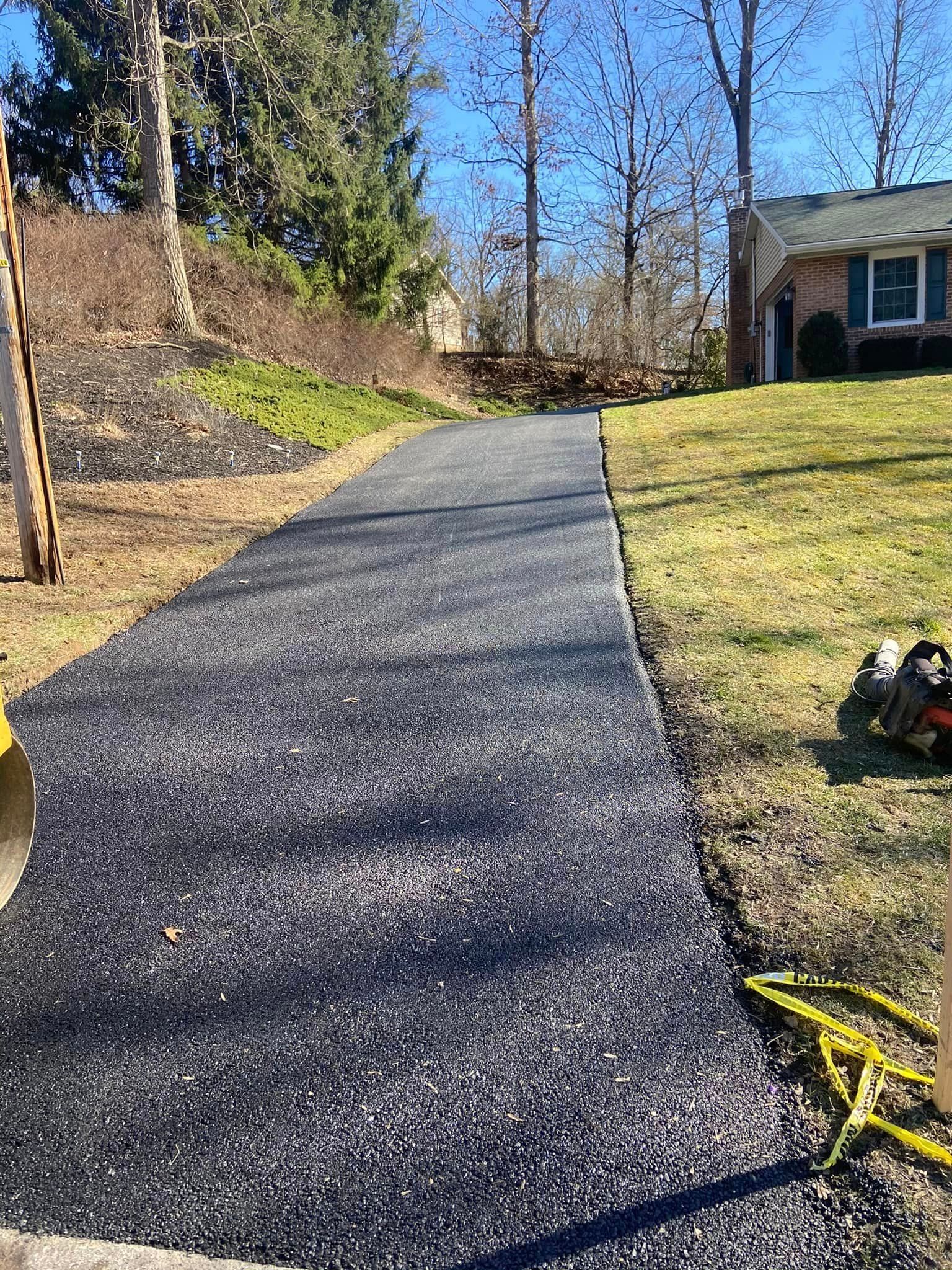 A asphalt driveway is being built in front of a house.