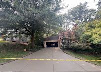 Tree-lined driveway leading to a covered garage entrance behind yellow caution tape