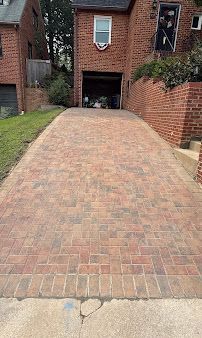 Brick driveway leading to a brick house with a garage entrance at the top.
