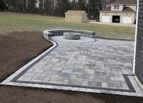 Paver patio with curved border and built-in fire pit beside a house in a backyard