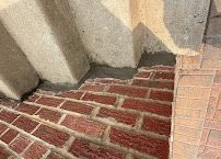 Red brick stairway beside a beige stucco wall and tan tiled sidewalk