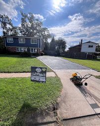 Suburban house with a lawn, driveway, and a lawn mower on the sidewalk under a sunny sky