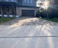 Suburban driveway leading to a garage, with sunlight casting long shadows across the pavement.