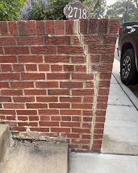Brick wall with house number 2718 beside a sidewalk and parked car