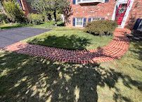 Brick house front yard with curved brick edging around a grassy garden bed