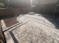 Backyard patio with gray pavers and curved concrete borders in bright sunlight