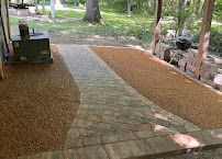 Wooden boardwalk path through a wooded park, with gravel on both sides and a bench on the left.