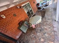 Patio table and chairs beside a brick building, with a glass door and tiled walkway