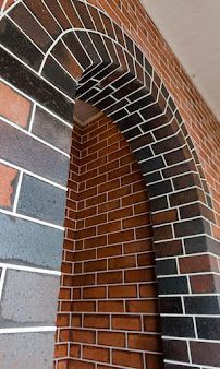 Brick archway with black and red bricks against a gray wall and white trim