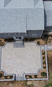 Aerial view of a house with a large paved front patio and steps leading to the entrance.