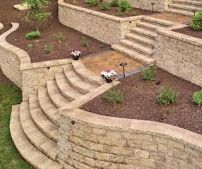 Stone terraced retaining wall and steps with two remote-controlled cars on a landscaped hillside