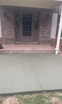 Brick front porch with a centered front door, red brick steps, and a concrete walkway leading up to it
