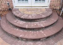 Three rounded stone steps leading to a brick doorway with white French doors above.