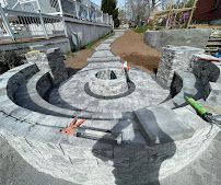 Stone fire pit with curved seating in a backyard patio under construction