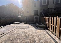 Sunny backyard patio with concrete slab, wooden fence, and apartment building balconies