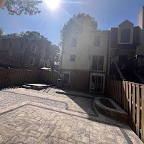 Paved courtyard between townhouses with bright sun glare and wooden fencing.