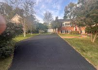 Driveway leading to a brick house with trees and green lawn at dusk