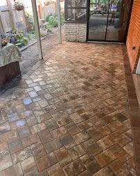 Brick-paved patio with a covered seating area and sliding glass doors to a house
