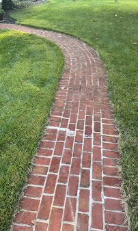 Curving red brick walkway through a green grassy lawn