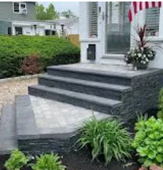 Curved brick retaining wall beside brick patio and steps in a landscaped garden