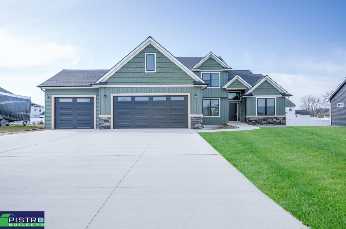 A large green house with two garage doors is for sale.