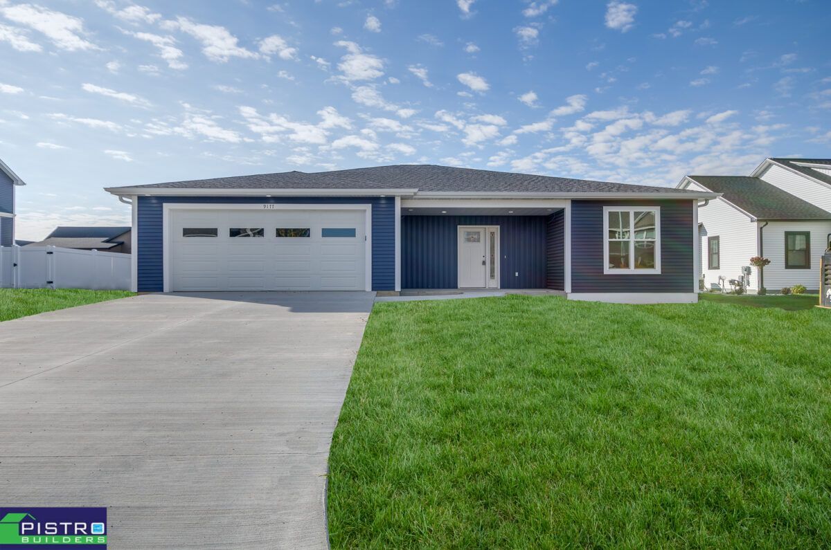 A blue house with a white garage door is for sale.