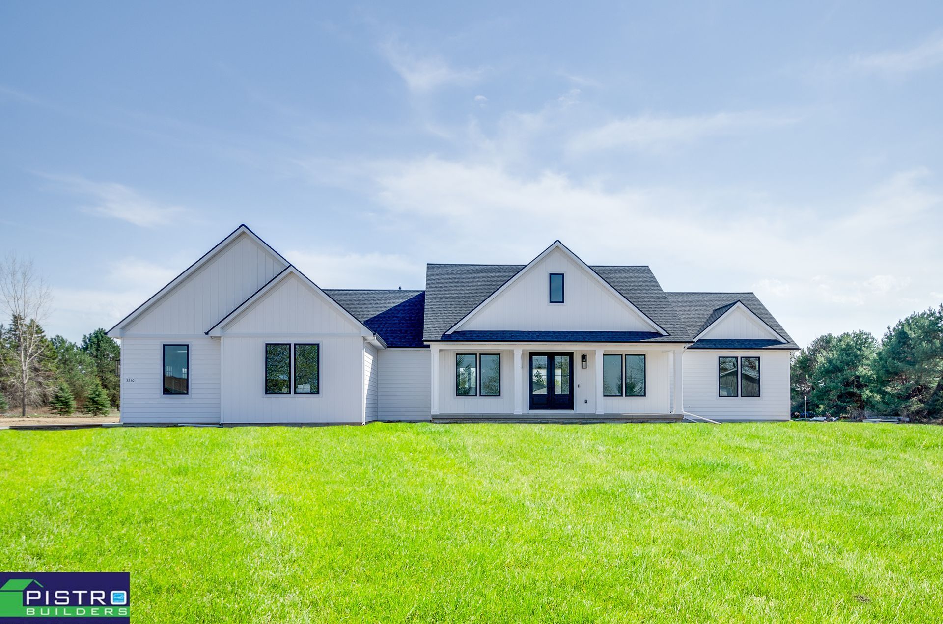 White house with black trim and roof, set on a green lawn