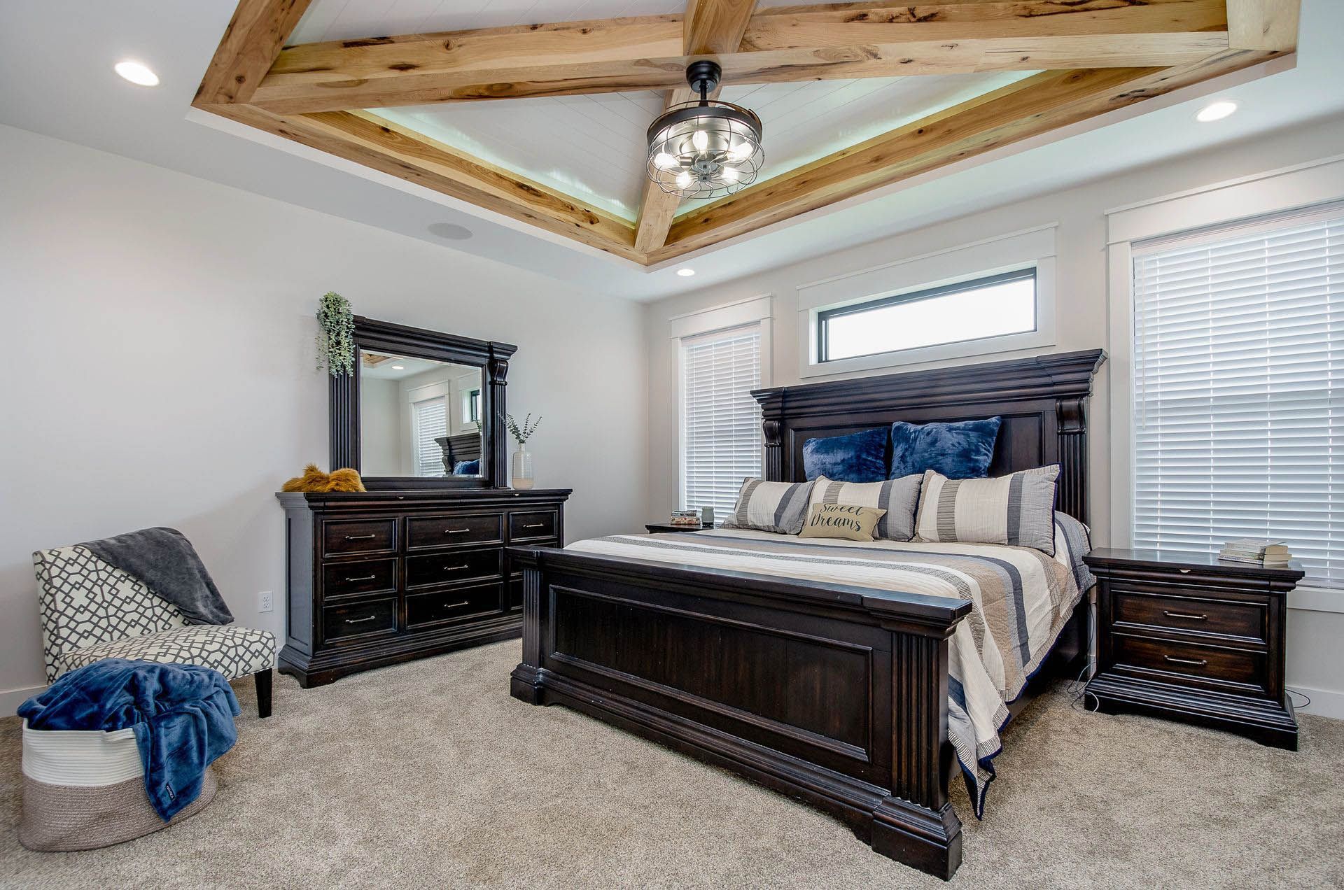 Bedroom with dark wood furniture, beige carpet, and decorative wooden ceiling beams