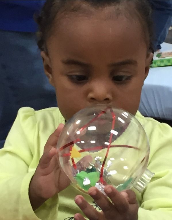 Child examining a clear plastic ball with a red line and green pieces inside