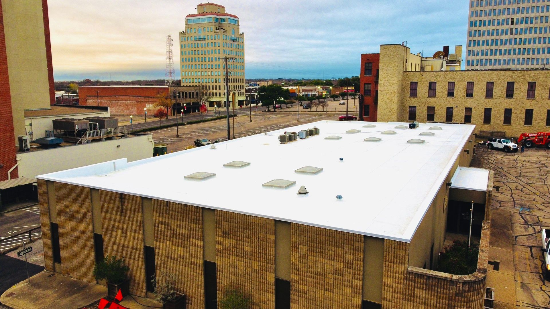 Building rooftops in a city landscape with a white roof.