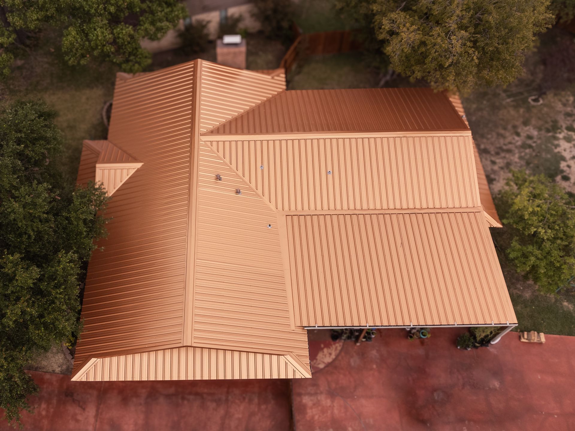 An aerial view of a copper-colored roof on a house in a wooded area.