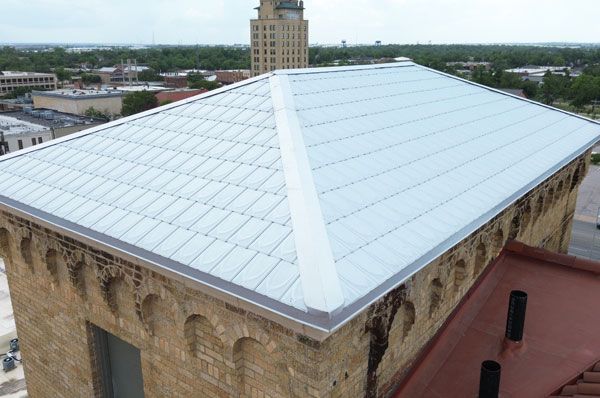 Metal roof on a brick building with a taller building in the background
