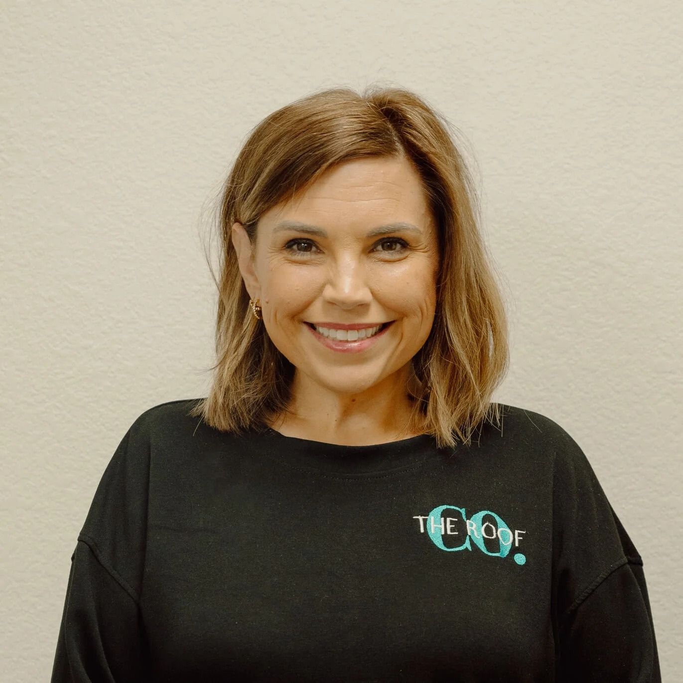 Woman with brown hair wearing a black sweatshirt that says 
