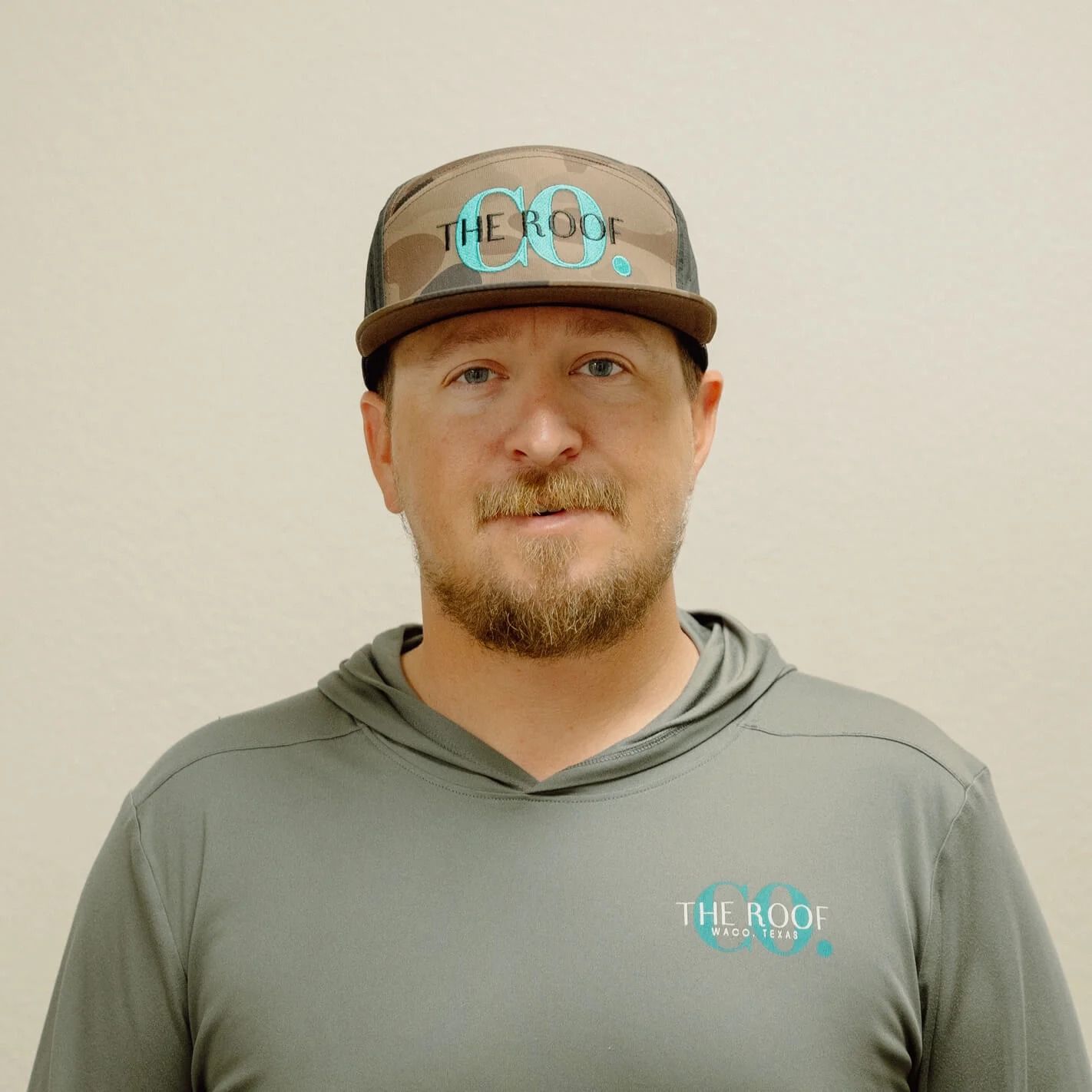A man in a camouflage hat and gray hoodie with 