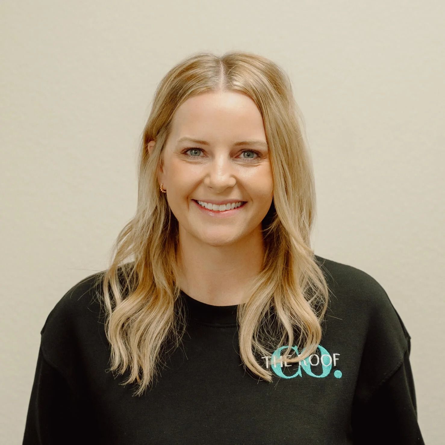 Blonde woman with a friendly smile wearing a black sweatshirt that has 