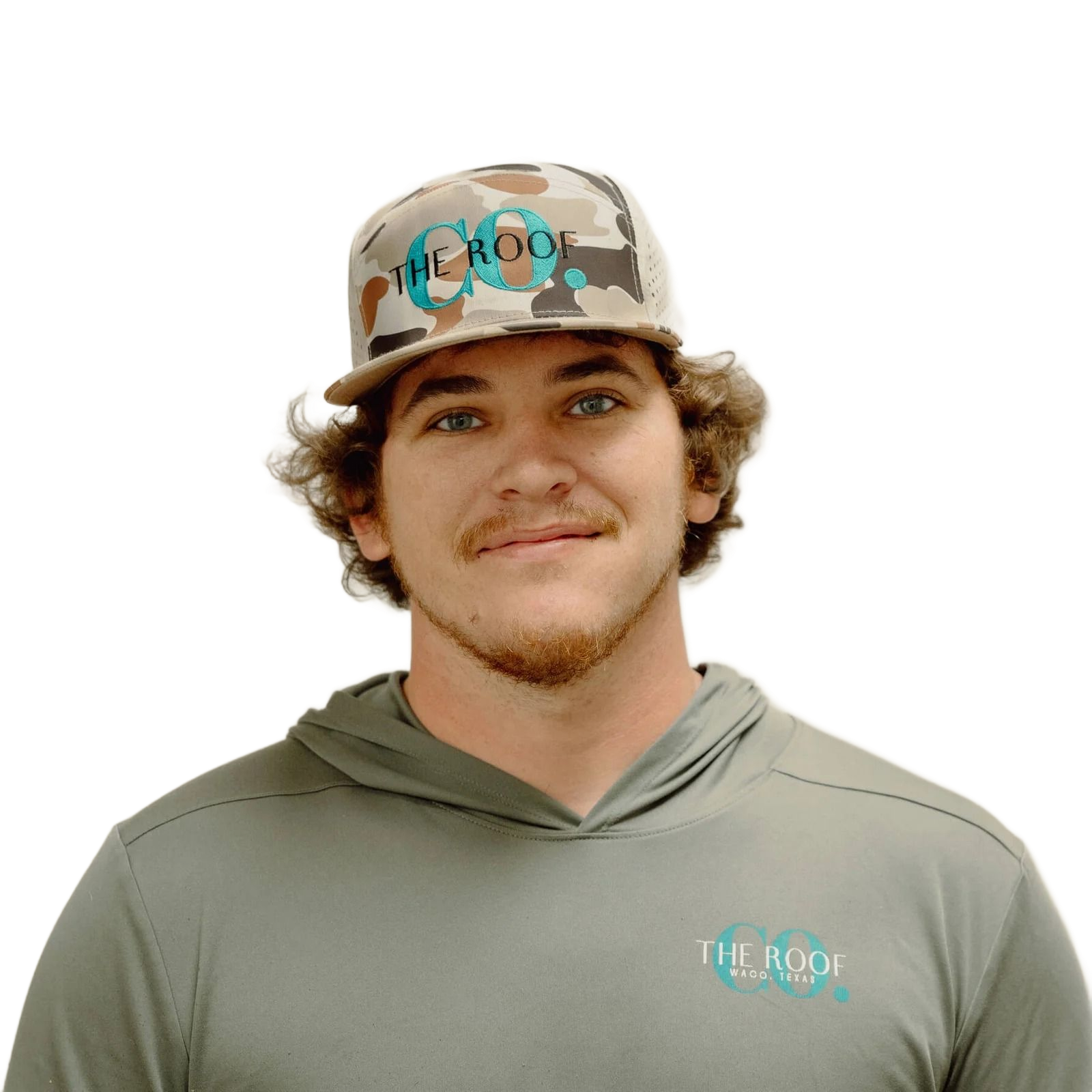 A young man with curly brown hair, wearing a camouflage hat and a gray hooded shirt, smiling.